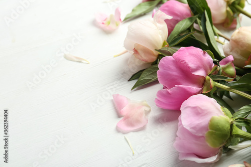 Beautiful peonies on white wooden table, closeup. Space for text
