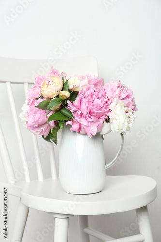 Beautiful fragrant peonies in jug on white chair © New Africa