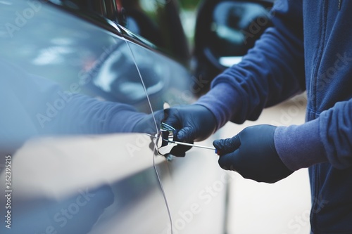 thief using a tool to break into a car.