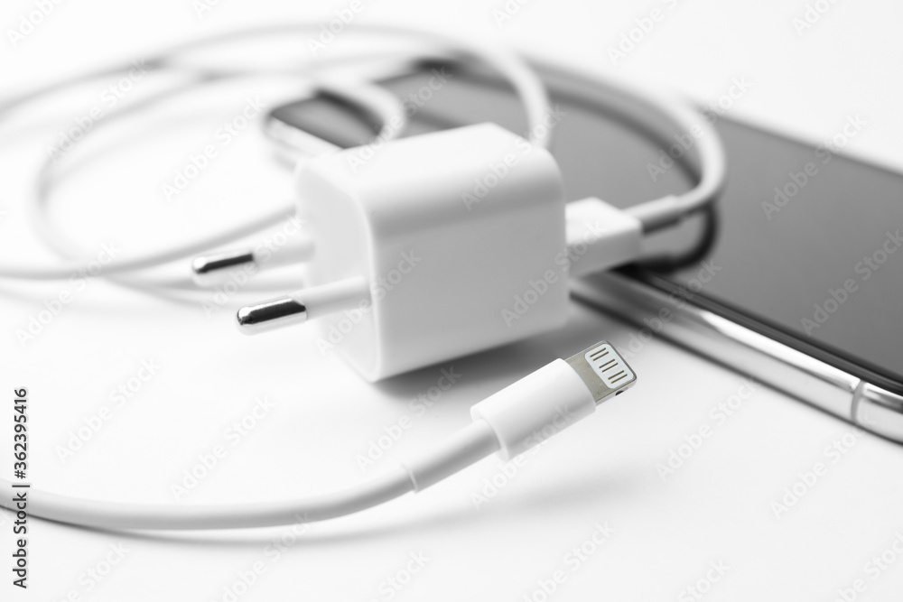 Smartphone and charging cable with adapter on white background, closeup Smartphone and charging cable with adapter on white background, closeup