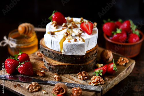 Selective focus. Macro. Composition with Camembert cheese, nuts, strawberries and honey. Luxury snack. Healthy dessert. Costly healthy desserts presentation.