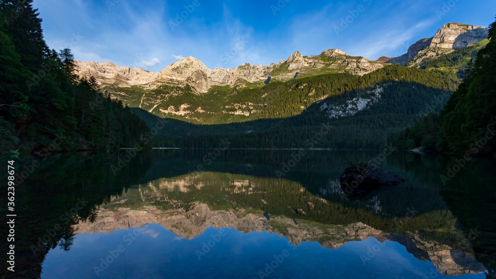 Mountains reflected at dawn into Tovel lake water, Italy