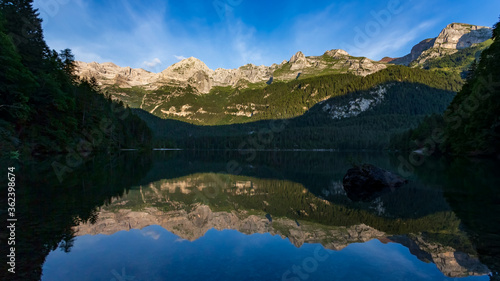 Mountains reflected at dawn into Tovel lake water  Italy