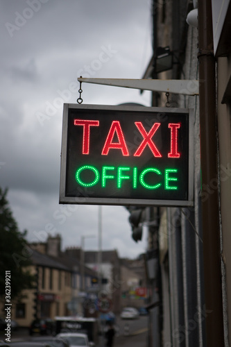 Red and green neon Taxi office sign. Bright neon lights advertising taxis