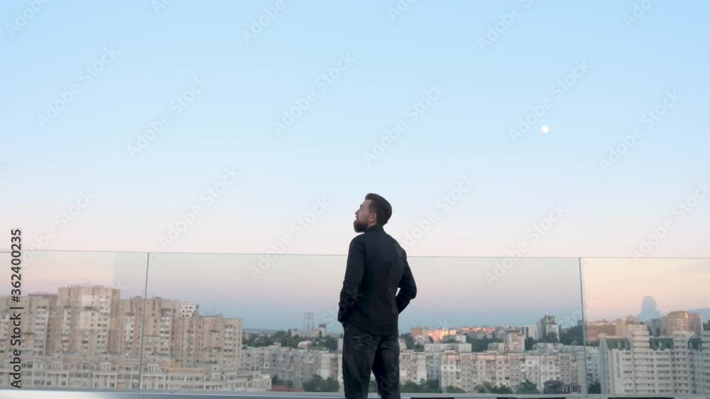 Businessman staying on his house roof and admiring the view, sunrise/sunset and city view from the high Businessman staying on his house roof and admiring the view, sunrise/sunset and city view from the high