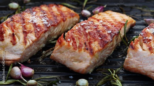 Grilled salmon fillets on a grill plate sprinkled with salt flakes