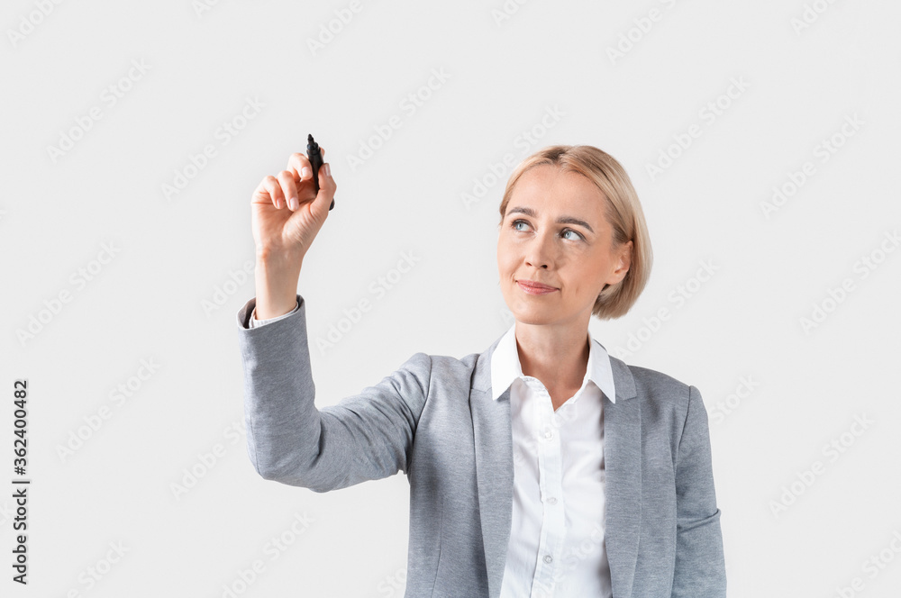 Attractive business lady writing or drawing on virtual screen against light background, space for design Attractive business lady writing or drawing on virtual screen against light background, space for design