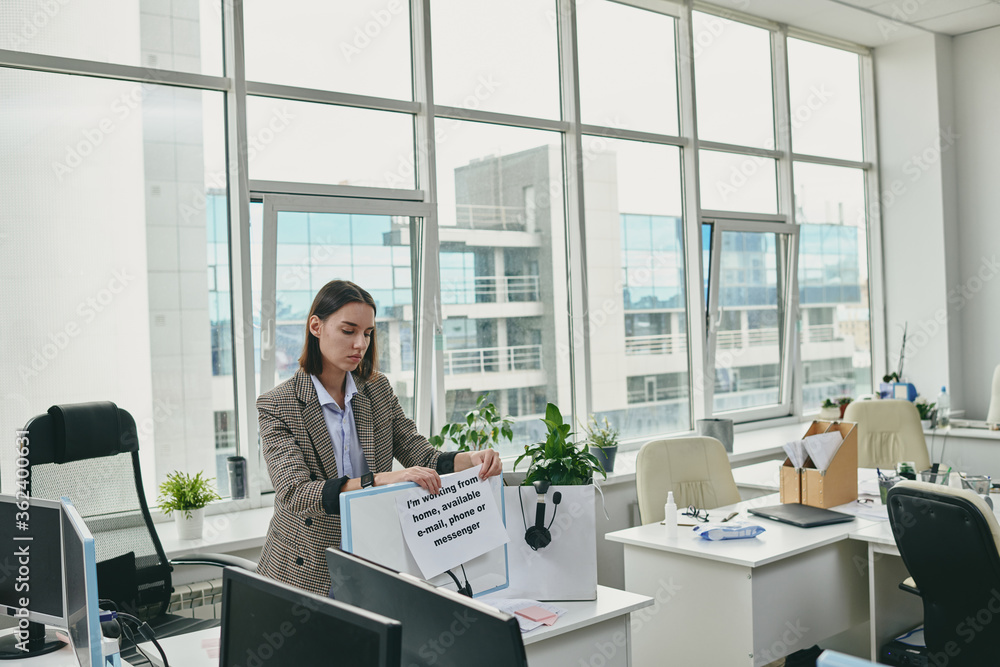 Young elegant secretary putting paper with note about her working from home Young elegant secretary putting paper with note about her working from home