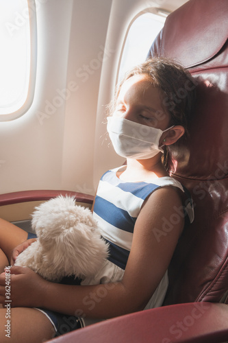 Boy in airplane with facial mask. Coronavirus outbreak. Safe travel with young children and babies. Children flying an airplane with surgical masks.