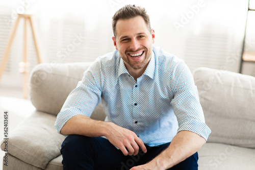 Glad man having rest at home on the sofa