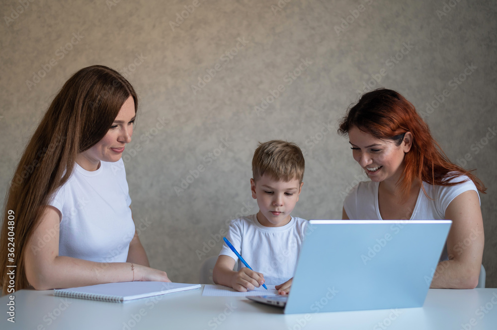 Two women help the boy do school homework. Female tutor teaches a child at home in the kitchen. The school teacher conducts an individual lesson. Mother helps her son to study. Two women help the boy do school homework. Female tutor teaches a child at home in the kitchen. The school teacher conducts an individual lesson. Mother helps her son to study.