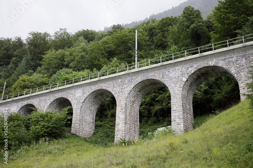 A beautiful road bridge with arches is surrounded by greenery