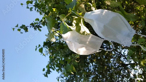 Surgical face mask close-up on a background of green leaves of trees, on a background of blue sky and sunlight. Drying medical face masks. Protecting from the coronavirus outbreak and pandemic.Freedom