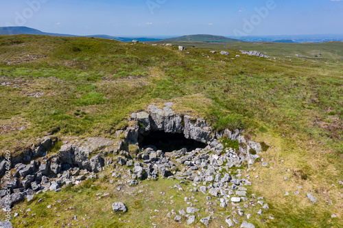 Aerial view of the entrance to an underground cave system on remote moorland (Chartist Cave, Wales, UK)