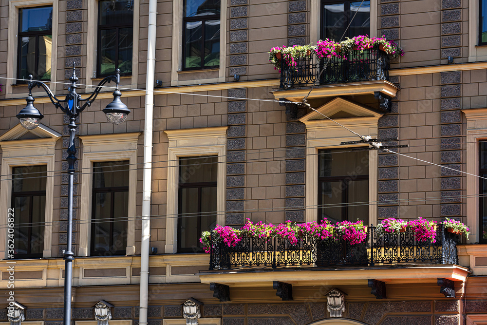 a fragment of the facade of a building with balconies decorated with flowering petunias