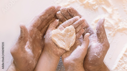 Father And Daughter Holding Heart-Shaped Dough On Hands Indoor  Closeup