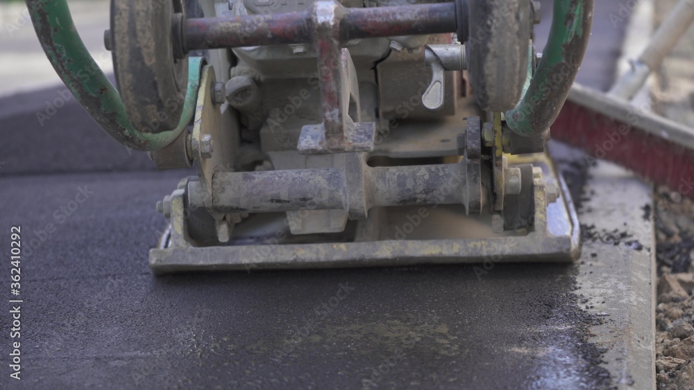 Vibratory asphalt paving machine on the sidewalk filmed close-up.Road works,pavement repair,hard work.Video clip Vibratory asphalt paving machine on the sidewalk filmed close-up.Road works,pavement repair,hard work.Video clip