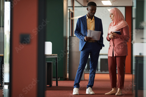 Tableau sur toile Full length portrait of African-American man talking to young Muslim businesswom