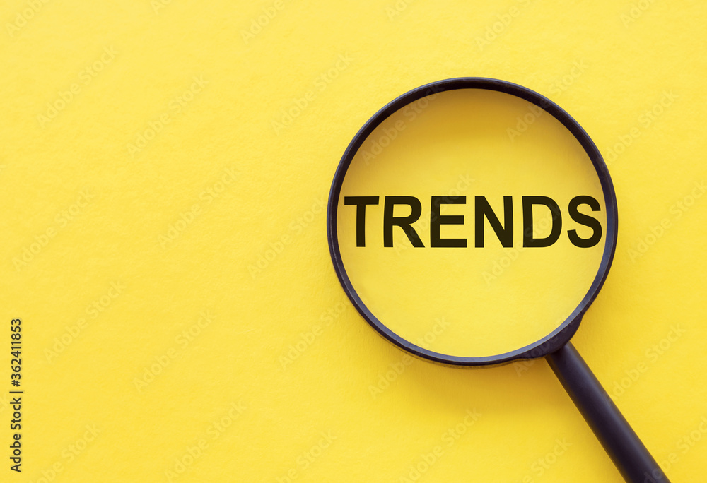 TRENDS text written on magnifier glasses, on yellow background. Main trend of changing something. Popular and relevant topics. New trends in business. Recent and latest trend. Evaluation methods. - obrazy, fototapety, plakaty 