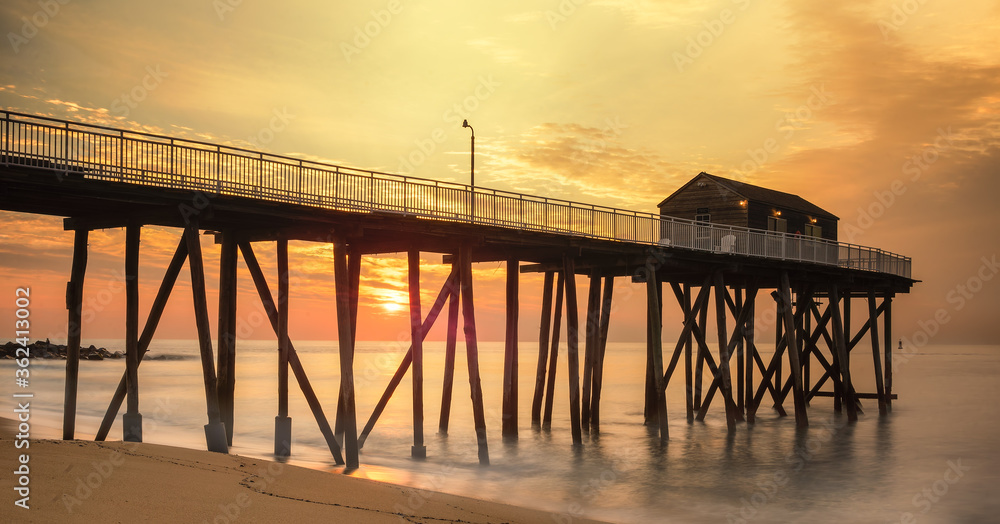 Long fishing pier, out into the Atlantic ocean, with long exposure in early morning sun. with golden color.