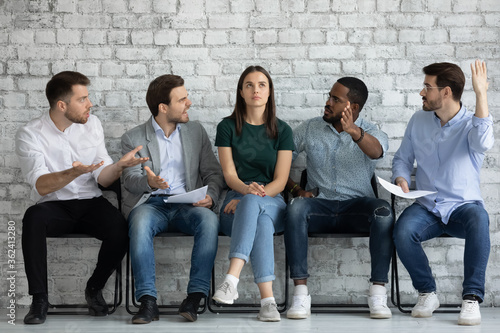 Multiracial men applicants sit on chairs in job interview queue show disrespect for girl kick out her. Disregard neglect, gender discrimination of women in business and professional occupation sphere