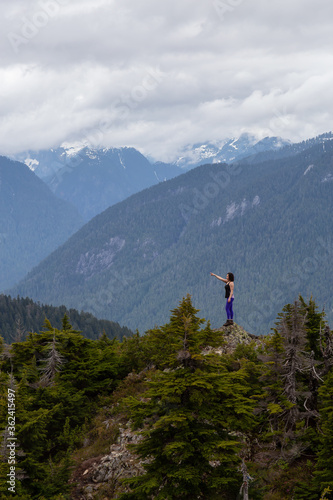 Adventurous Girl on top of a Mountain top with Canadian Nature Landscape in Background. Taken on Evan's Peak, Golden Ears Provincial Park, near Vancouver, BC, Canada.