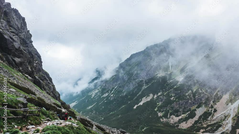 Mountain landscape with mountains surrounded with clouds. People climb the path to the mountain Time lapse. Mountain landscape with mountains surrounded with clouds. People climb the path to the mountain Time lapse.