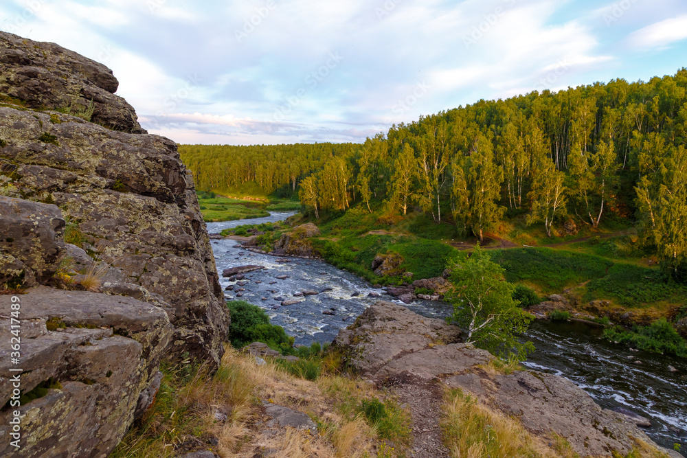 soft sun rays in evening over beautiful valley with mountain river and many rapids. Ural, Russia,