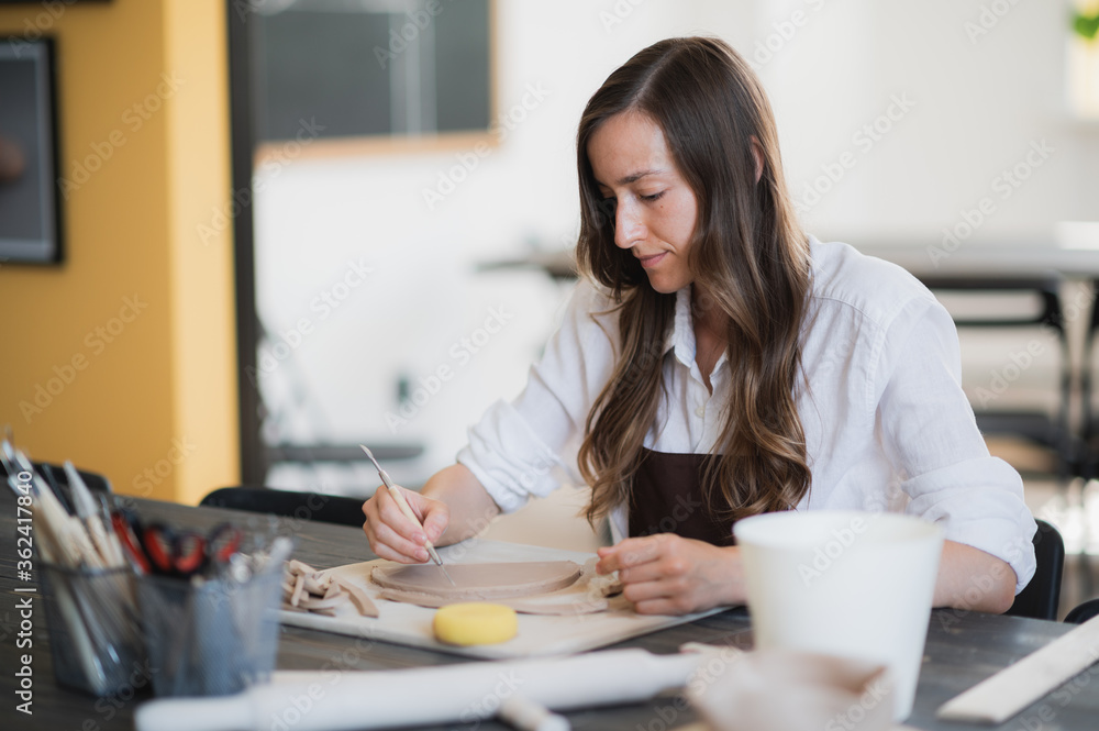 Artisan female potter prepares material for her pottery. Woman hands attach clay part to future ceramic product. Work close-up. Artisan female potter prepares material for her pottery. Woman hands attach clay part to future ceramic product. Work close-up.
