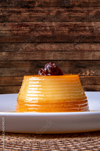 Homemade milk pudding with caramel cream. Traditional Brazilian dessert on a plate on wooden background. photo