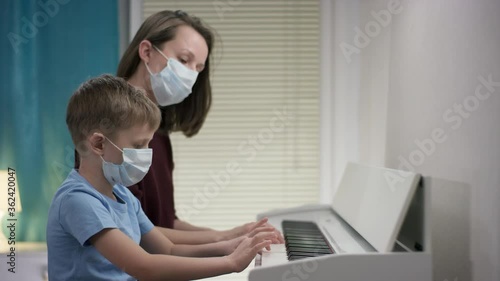 Health protection concept of a family members wearing health protective masks and entertaining themselves during self-isolation by playing the piano photo