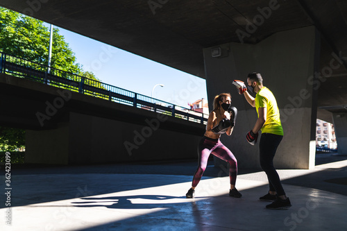 Spanish Woman Training Boxing with Coach Outdoors. Boxing Concept.