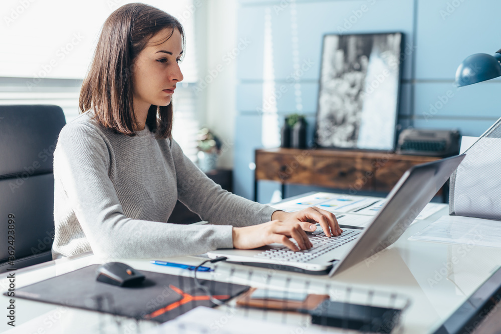 Woman using laptop while sitting at her desk. Businesswoman in the office working on laptop Woman using laptop while sitting at her desk. Businesswoman in the office working on laptop
