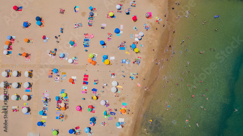 Aerial view of sandy beach with tourists swimming in beautiful clear sea water in Madeira island.