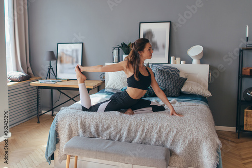 Young woman exercising at home. Morning workout in bedroom.