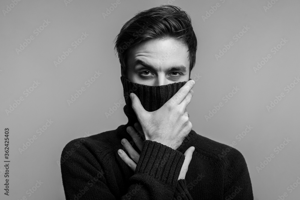 Portrait of stylish handsome young man in warm sweater, covering mouth with high collar and looking pensive thoughtful, male fashion, vogue concept. black and white, indoor studio shot isolated Portrait of stylish handsome young man in warm sweater, covering mouth with high collar and looking pensive thoughtful, male fashion, vogue concept. black and white, indoor studio shot isolated
