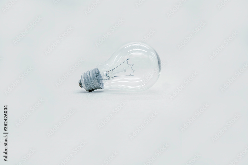 Incandescent light bulb lies on a light gray background. technology of the past, not reasonable consumption. Incandescent light bulb lies on a light gray background. technology of the past, not reasonable consumption.