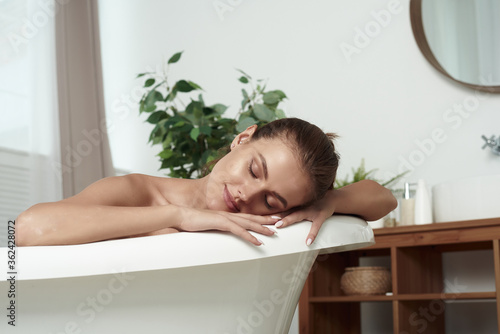 Close up of portrait of happy pretty woman with attractive smile relaxing while taking bath in bright apartment during romantic atmosphere