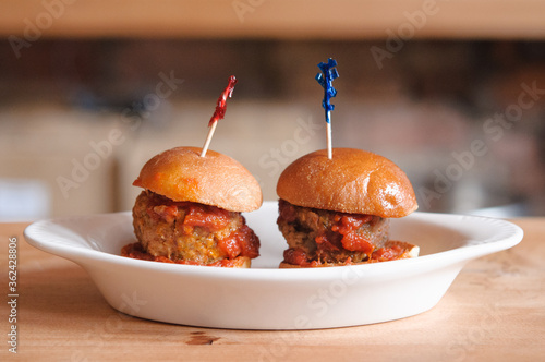 mini beef hamburger burger sliders with tomato sauce on brioche buns with toothpicks on a white plate