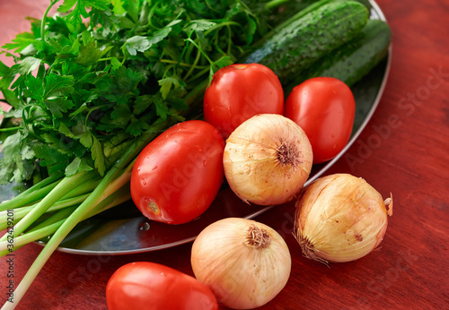 healthy food - fresh vegetables and greens on a wooden background, greens, onion and tomatoes