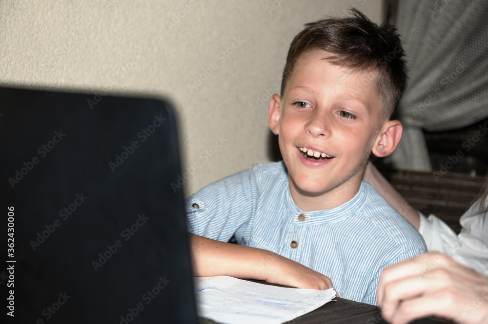A schoolboy is looking at a laptop screen. Online Education Concept A schoolboy is looking at a laptop screen. Online Education Concept