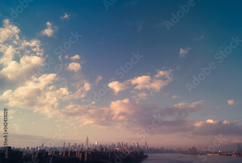 New York Cityscape deep past the east river at the magic hour with lush clouds, USA downtown skyline, Architecture and buildings with romantic concept © davi russo