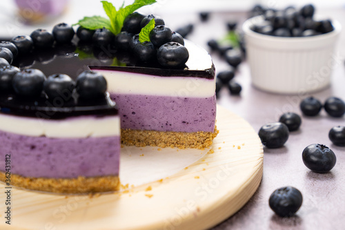 Round blueberry vegan cheesecake with berries and mint leaves on top