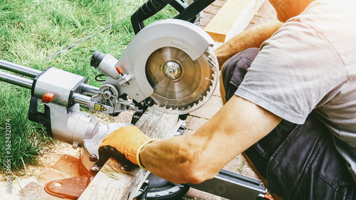 Canvas Print versatile craftsman working with wood to build a house on a summer day, DIY conc