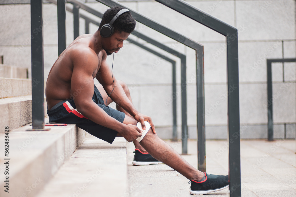 knee injury concept, afro american guy bandaging his leg with a bandage, a man injured his knee in training knee injury concept, afro american guy bandaging his leg with a bandage, a man injured his knee in training
