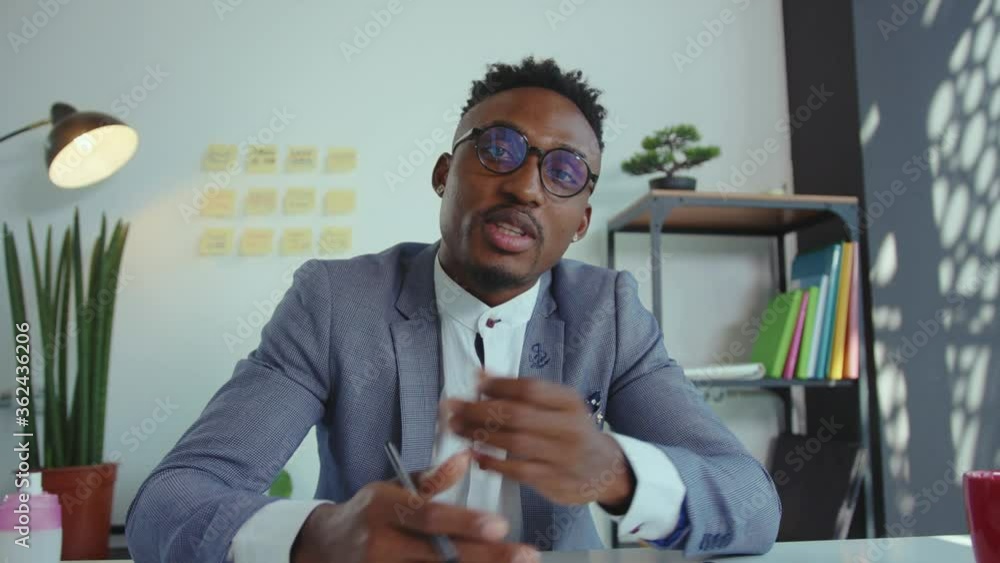 Smiling african american businessman in suit talking to camera shooting video blog or being webinar speaker worker conversation corporate filming slow motion Smiling african american businessman in suit talking to camera shooting video blog or being webinar speaker worker conversation corporate filming slow motion