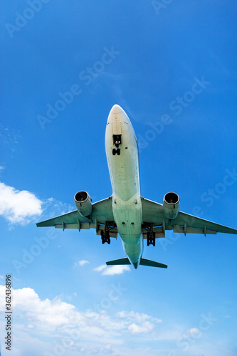 a passenger plane lands low over the sea, at an airport near the beach on a Sunny day