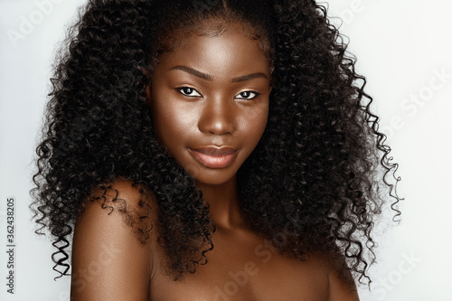 Fashion portrait of young beautiful african american woman with curly hair againstgray background