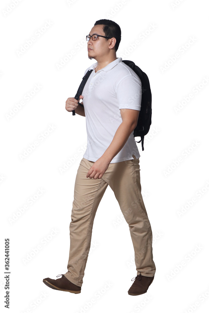 Full length portrait of Asian man wearing white shirt, khaki jeans and backpack standing walking, side view Full length portrait of Asian man wearing white shirt, khaki jeans and backpack standing walking, side view
