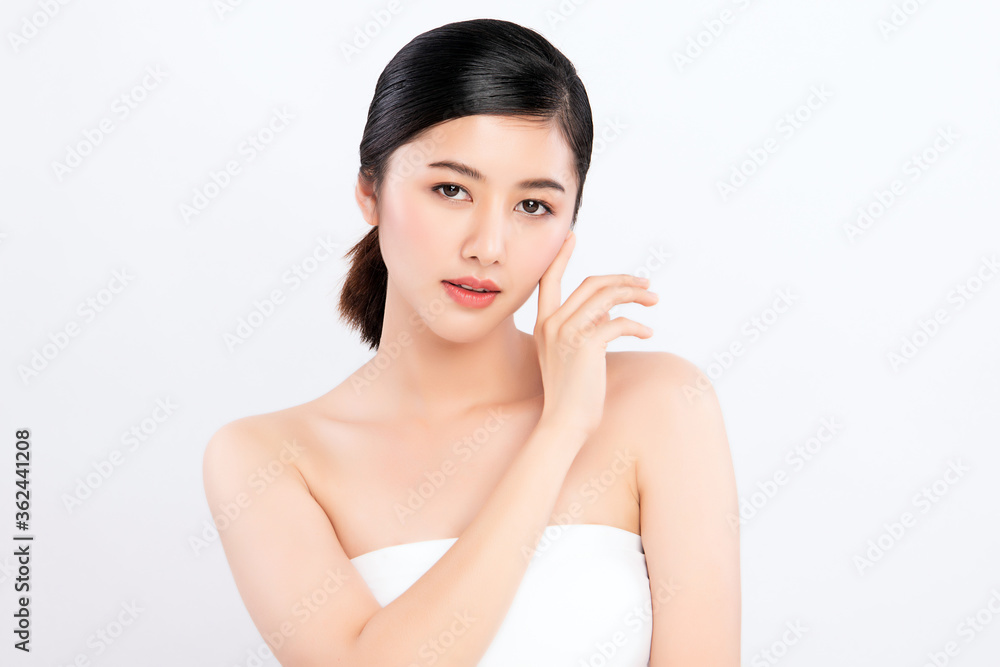 Beauty face. Smiling asian woman touching healthy skin portrait. Beautiful happy girl model with fresh glowing hydrated facial skin and natural makeup on white background